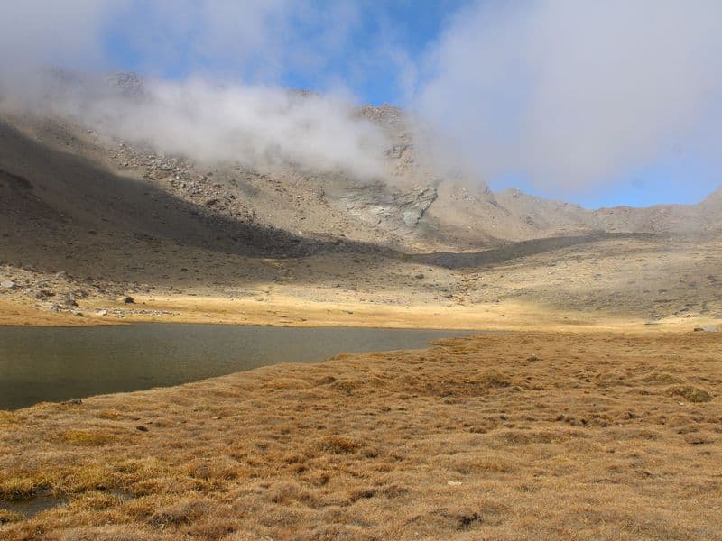 Breathtaking view of an alpine lake surrounded by misty mountains in Trevélez, Sierra Nevada.