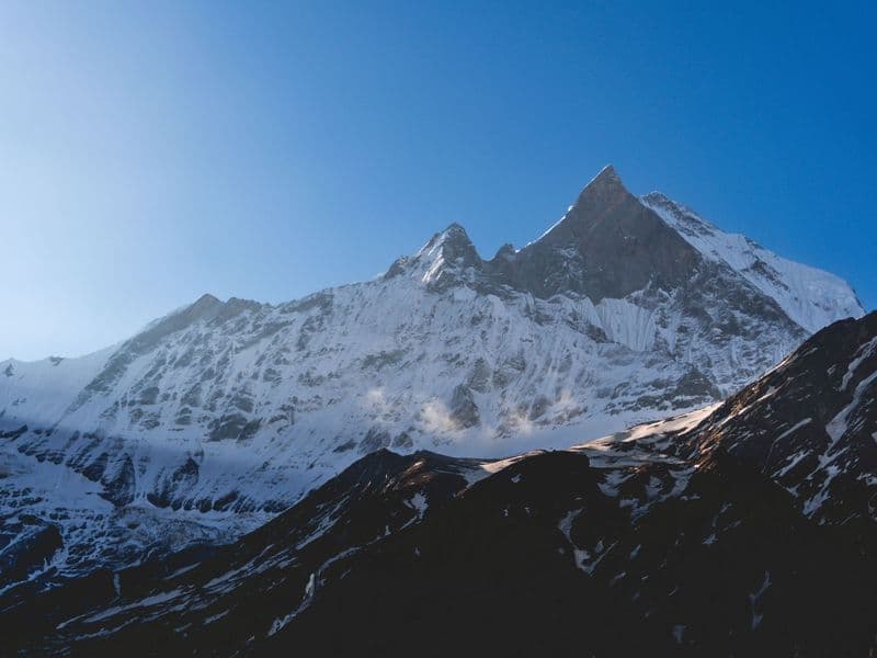 Breathtaking sunrise view of Machapuchare peak in the Himalayas, Nepal, with snow-covered slopes.