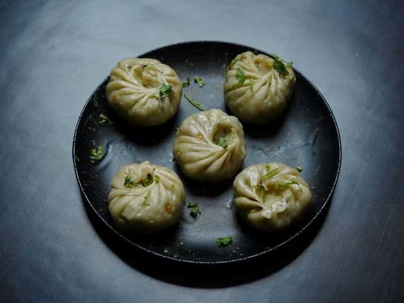 Plate of Tibetan dumplings (momos) garnished with herbs, perfect for food photography.