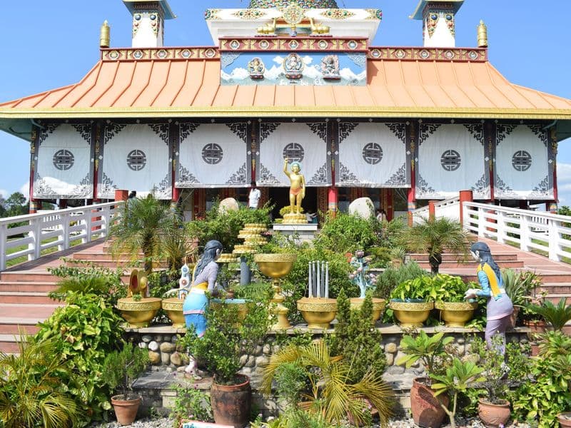 A vibrant Buddhist temple with garden decorations in Lumbini, highlighting religious architecture.
