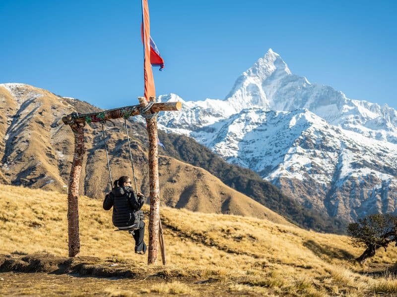 A woman enjoys a swing with a stunning view of the Annapurna mountain range in Pokhara, Nepal.