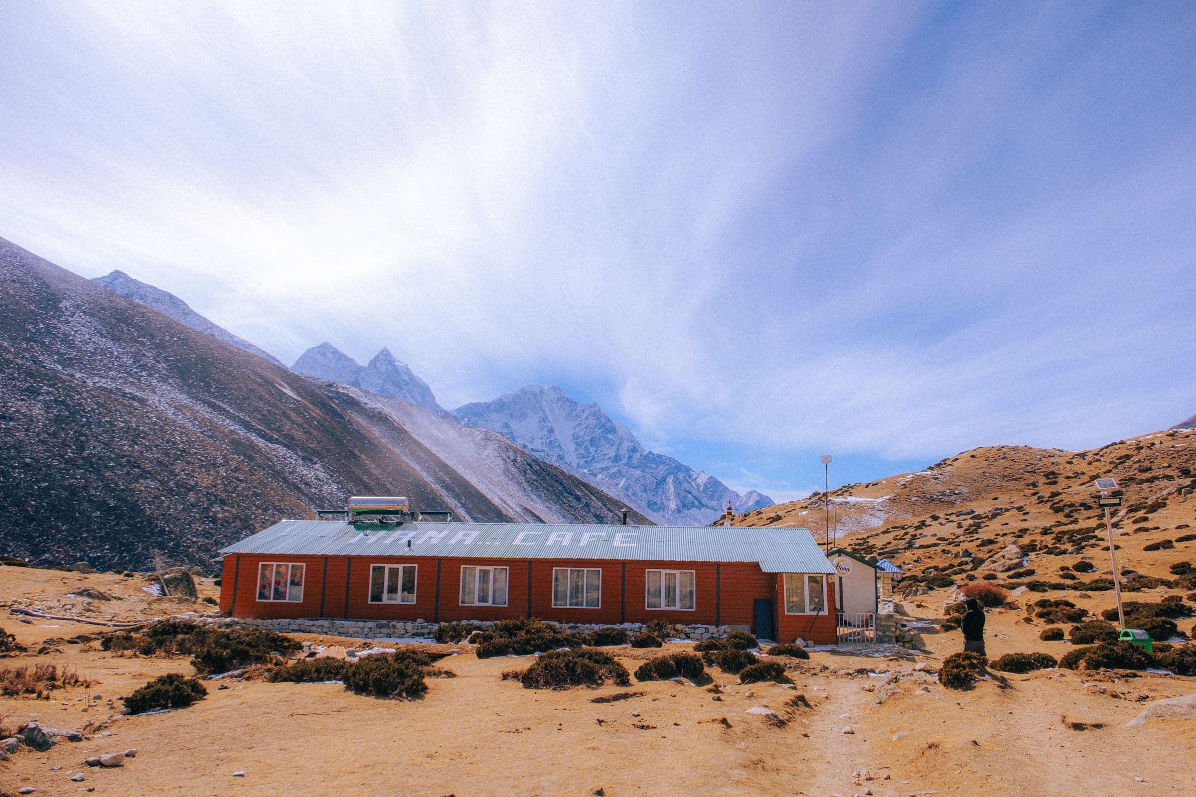Explore the serene Himalayan landscapes with a cozy cafe nestled amidst snowy peaks.