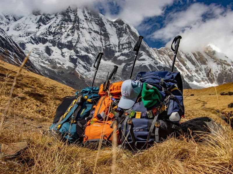 Backpacks rest at Annapurna's base under the snowy peaks, capturing trekking adventure in Nepal.